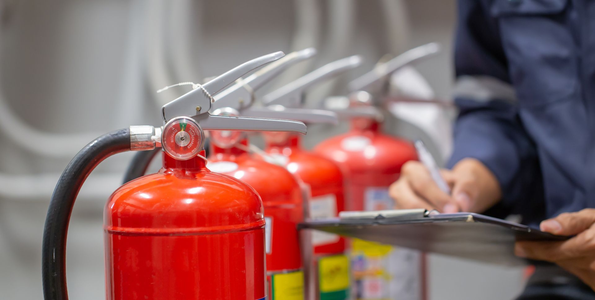 Professional inspecting a row of red fire extinguishers during a routine building safety check.