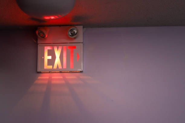 A red exit sign is lit up on a purple wall.