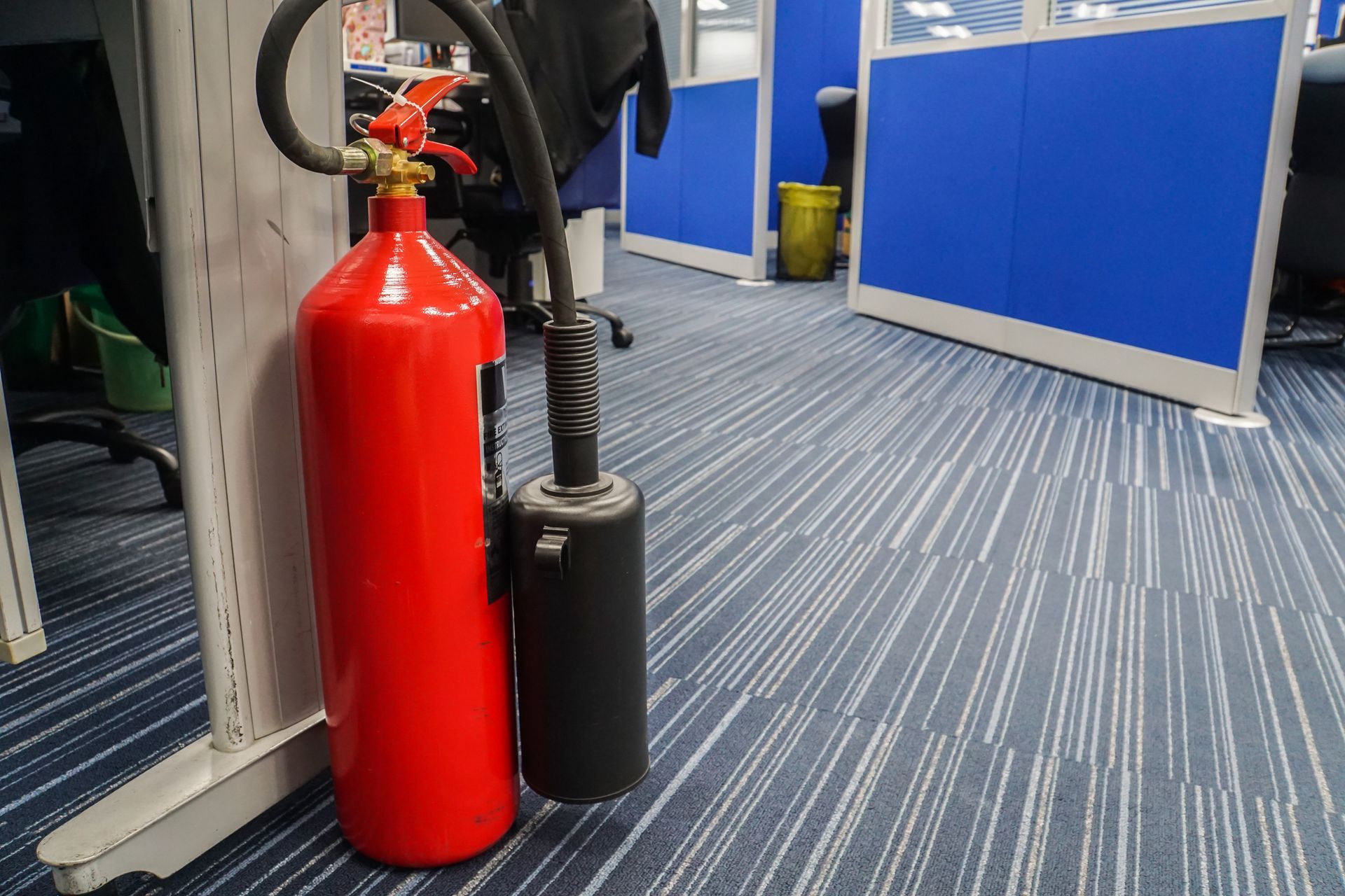 Red fire extinguisher in office, showcasing fire extinguisher refilling for workplace safety. Red fire extinguisher in office, showcasing fire extinguisher refilling for workplace safety.