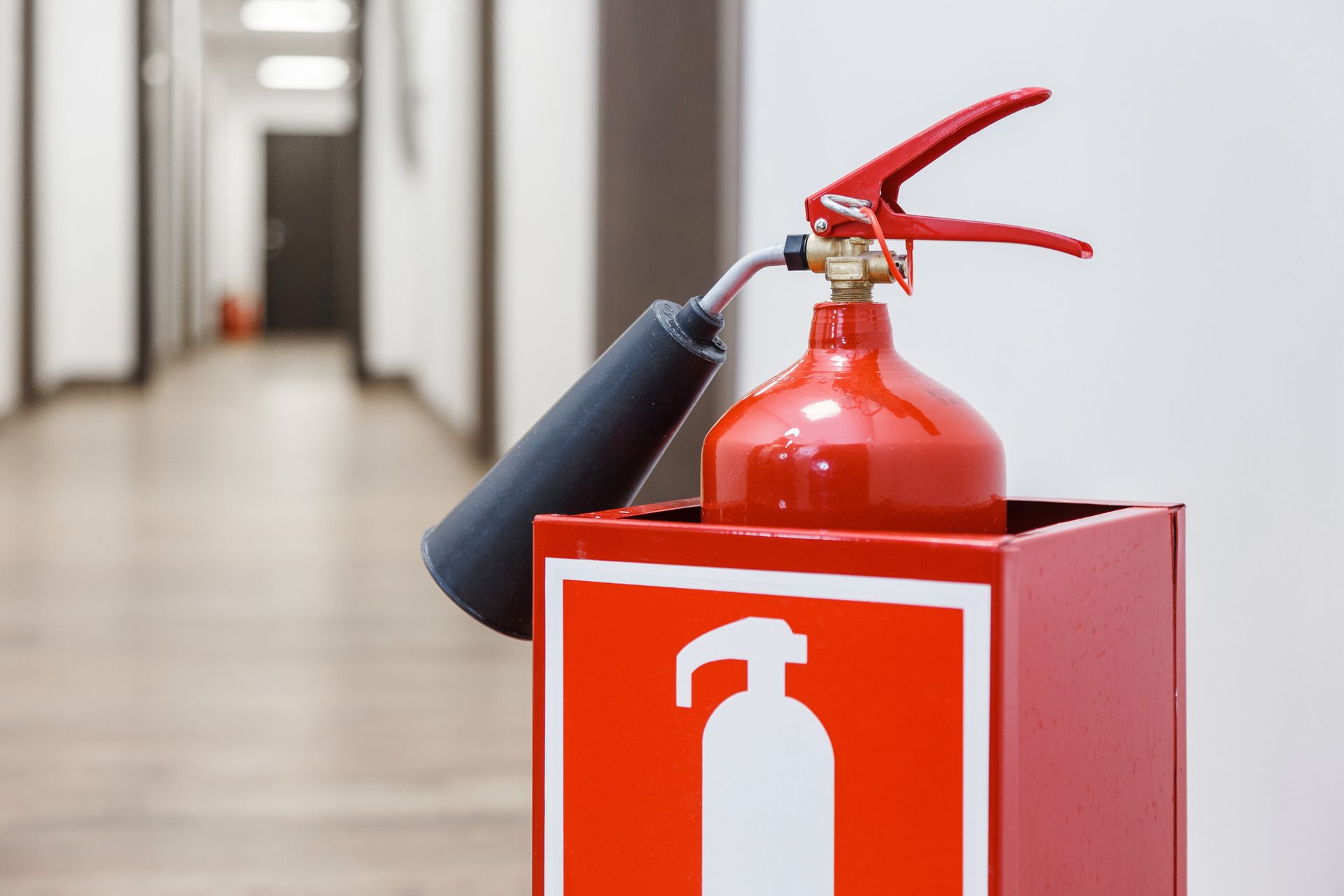 Red fire extinguisher in modern white hallway, highlighting fire extinguisher refilling.