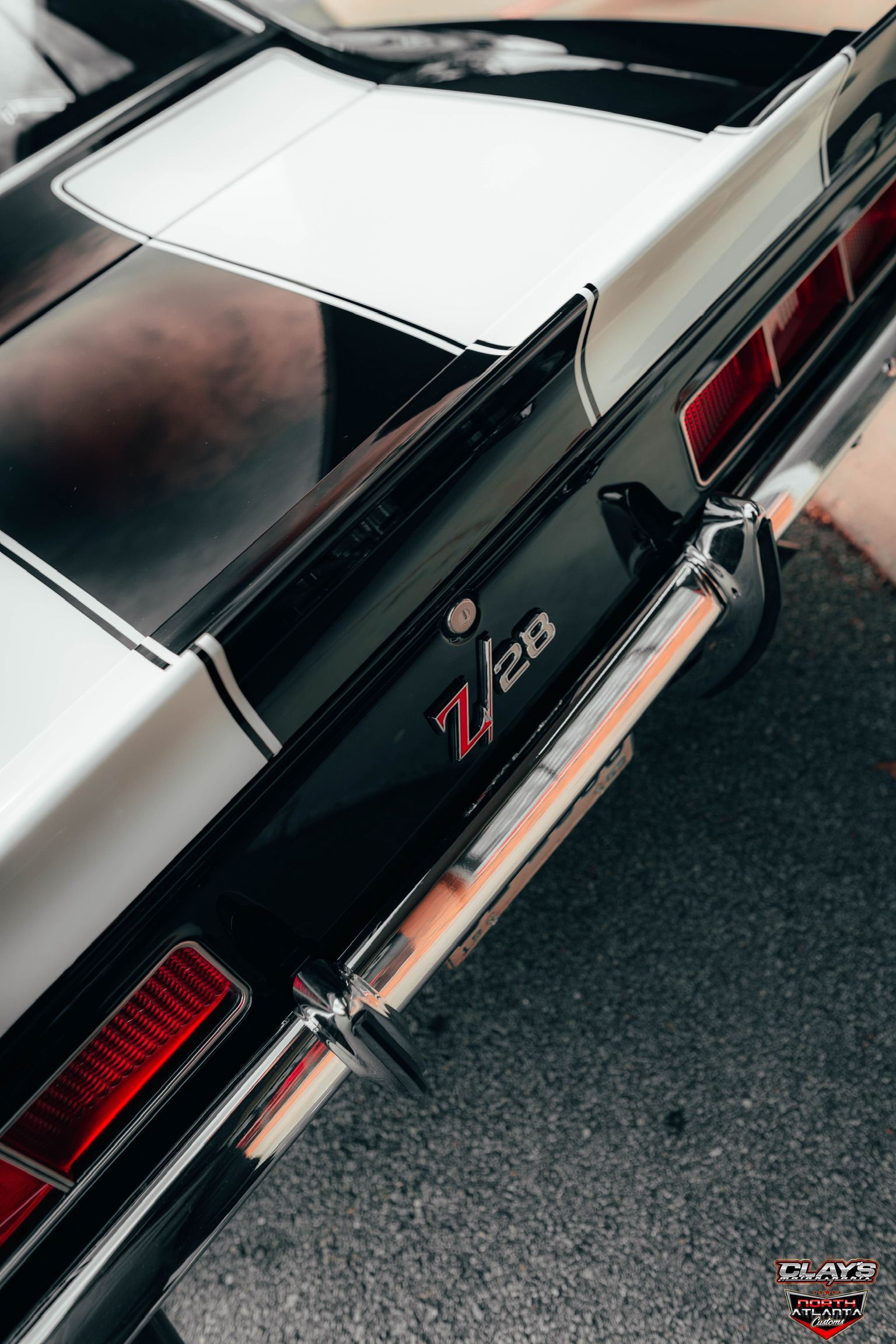 A black and white chevrolet camaro is parked on the side of the road.