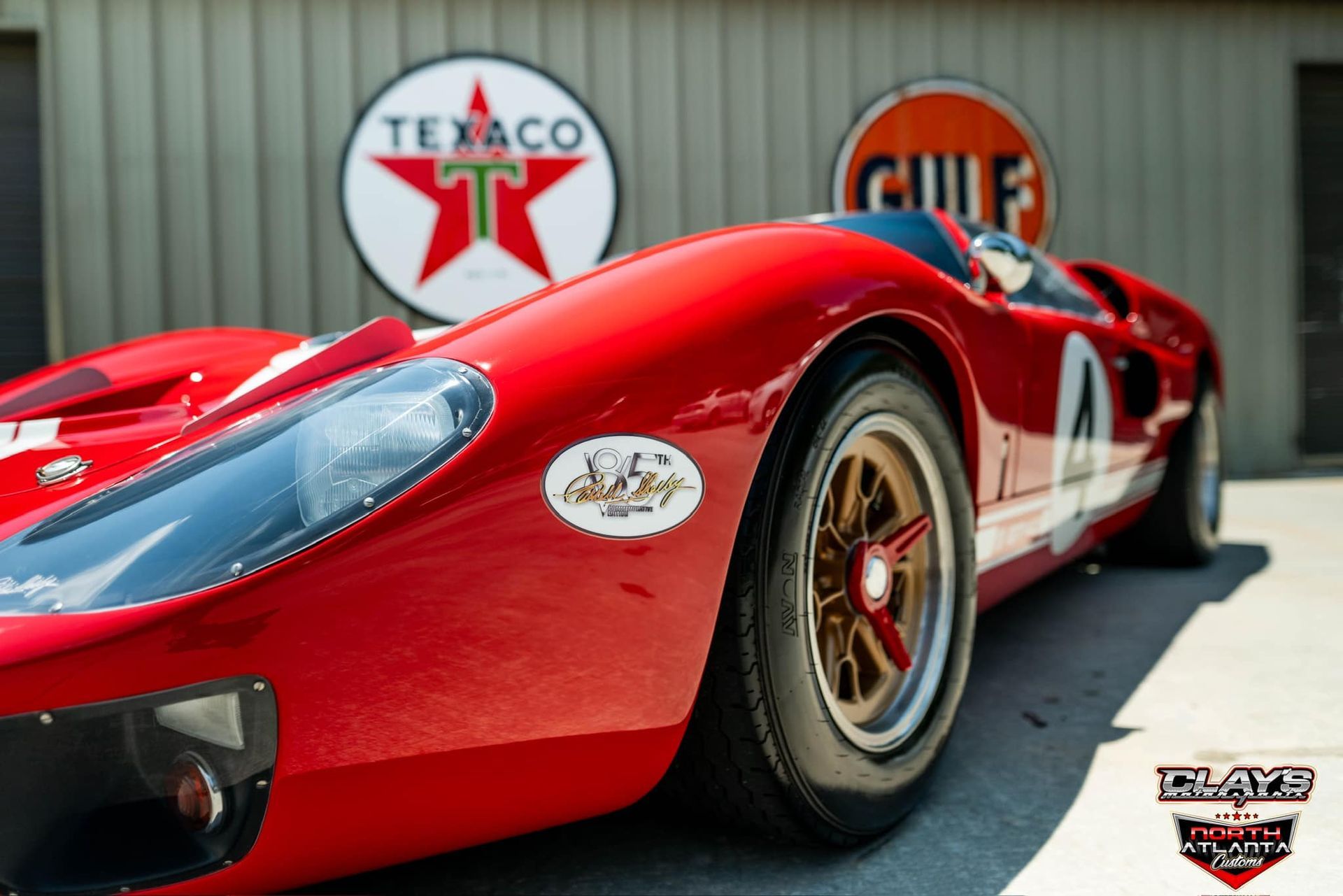 A red race car is parked in front of a texaco sign