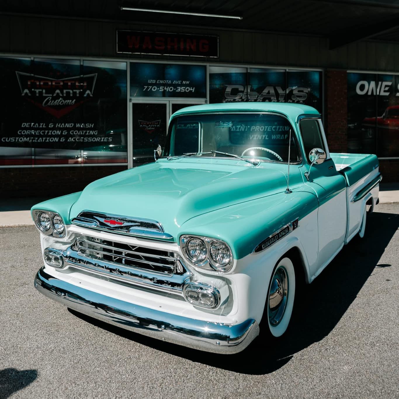 A black and white classic car is parked in front of a building.