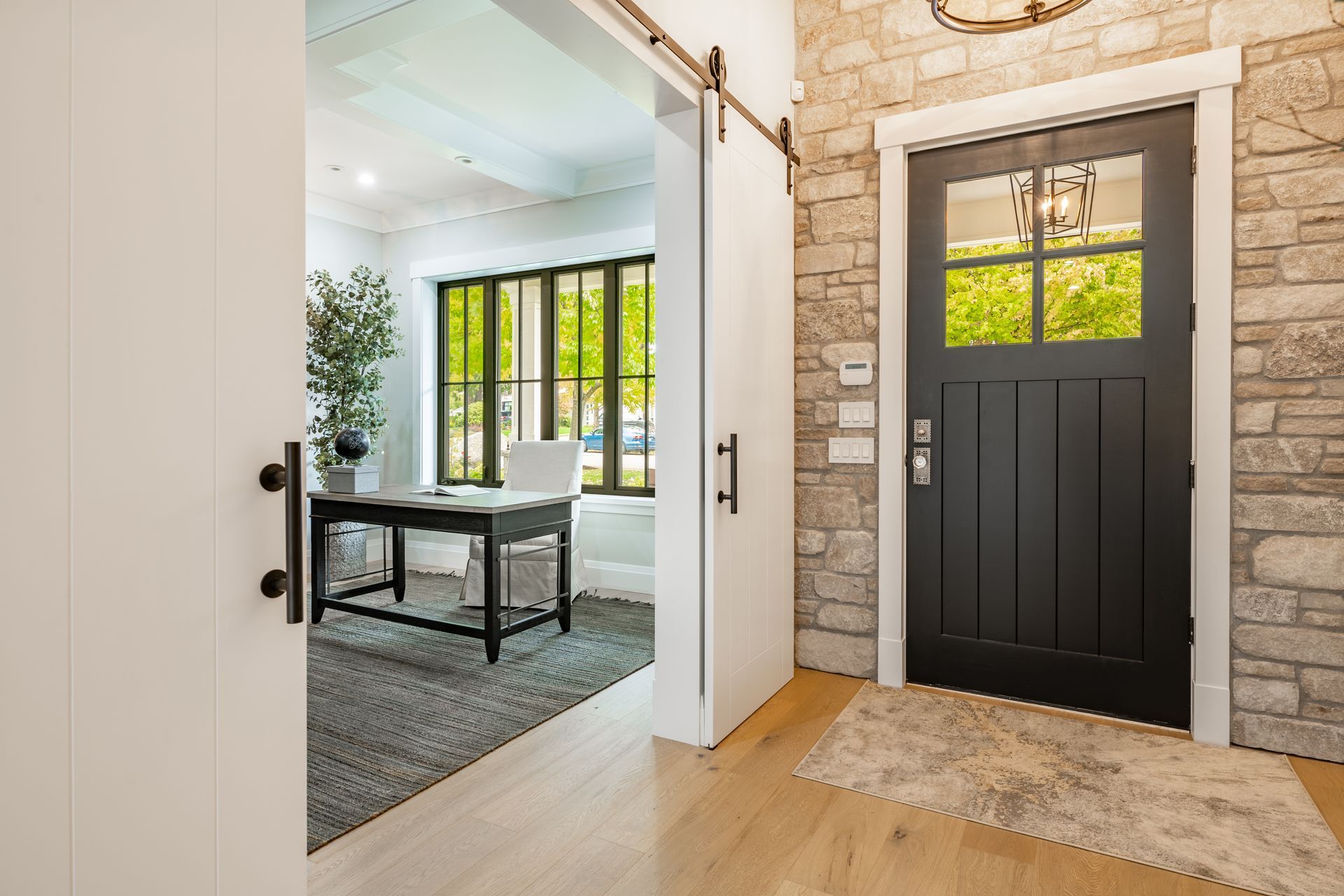 A black door is open to a living room with a desk and chair.