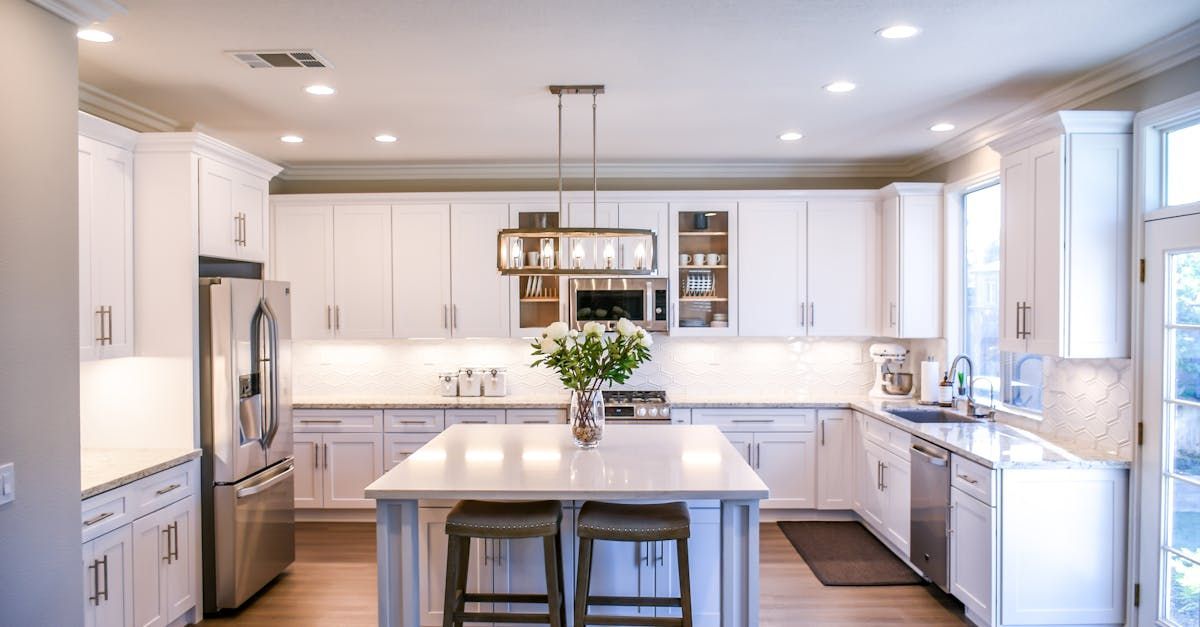 A kitchen with white cabinets , stainless steel appliances , and a large island.