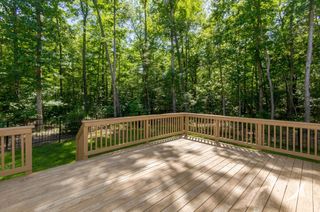 An empty wooden deck with a railing in the middle of a forest.