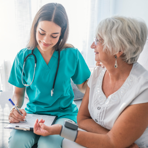 Nurse in teal scrubs taking blood pressure of a patient indoors.