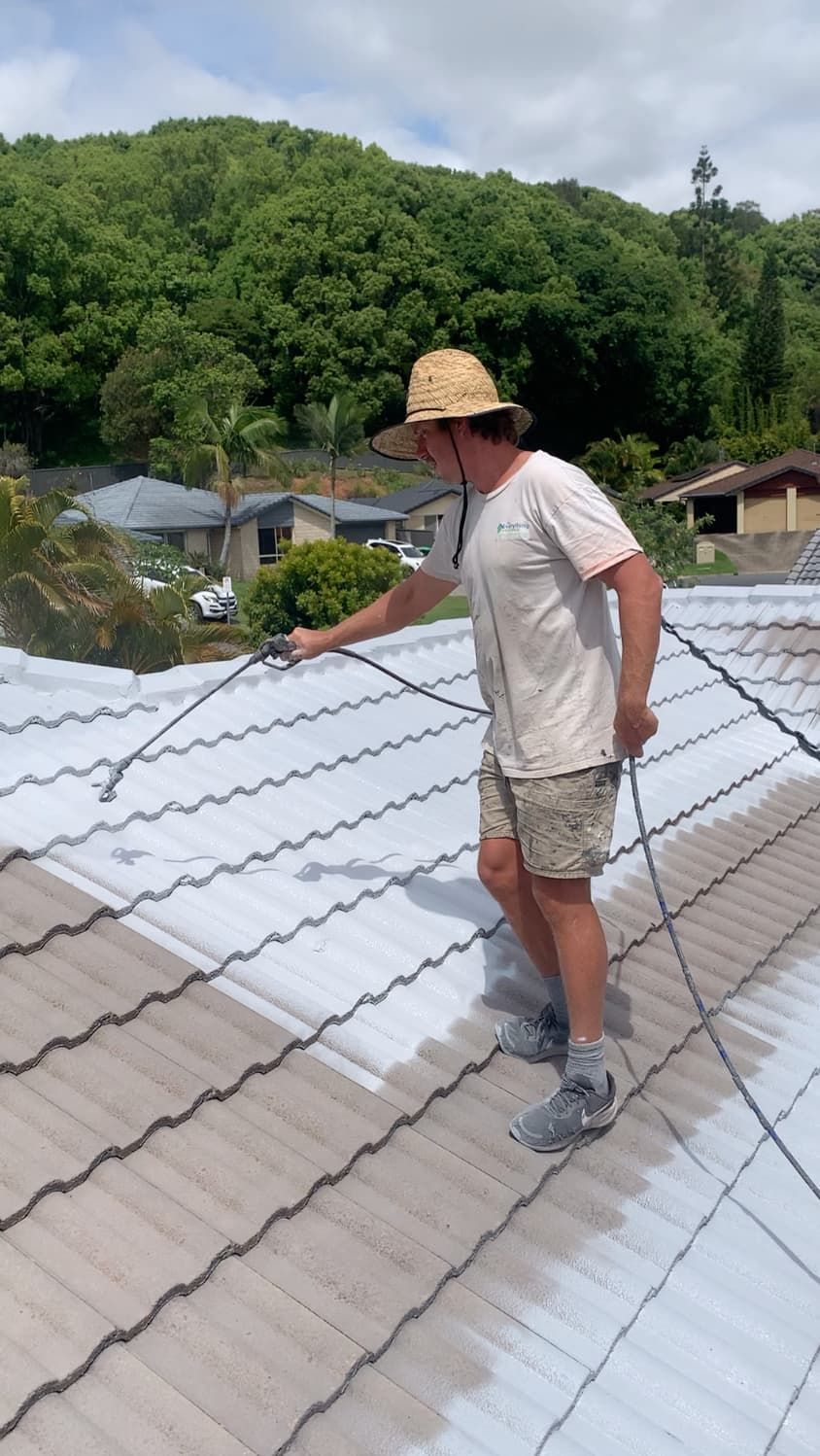 A man is painting a roof with a sprayer.