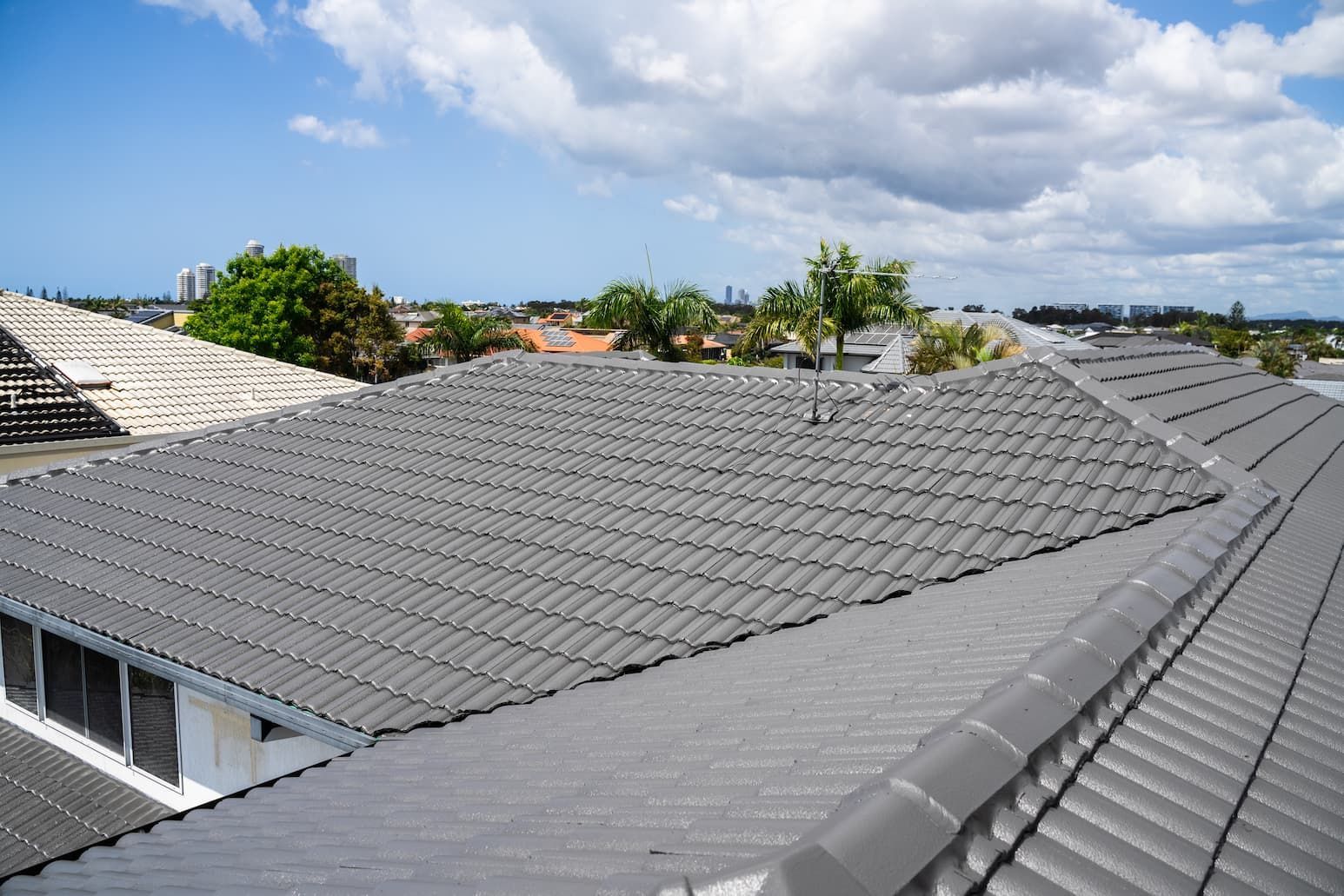 The roof of a house with a tiled roof and a blue sky in the background.