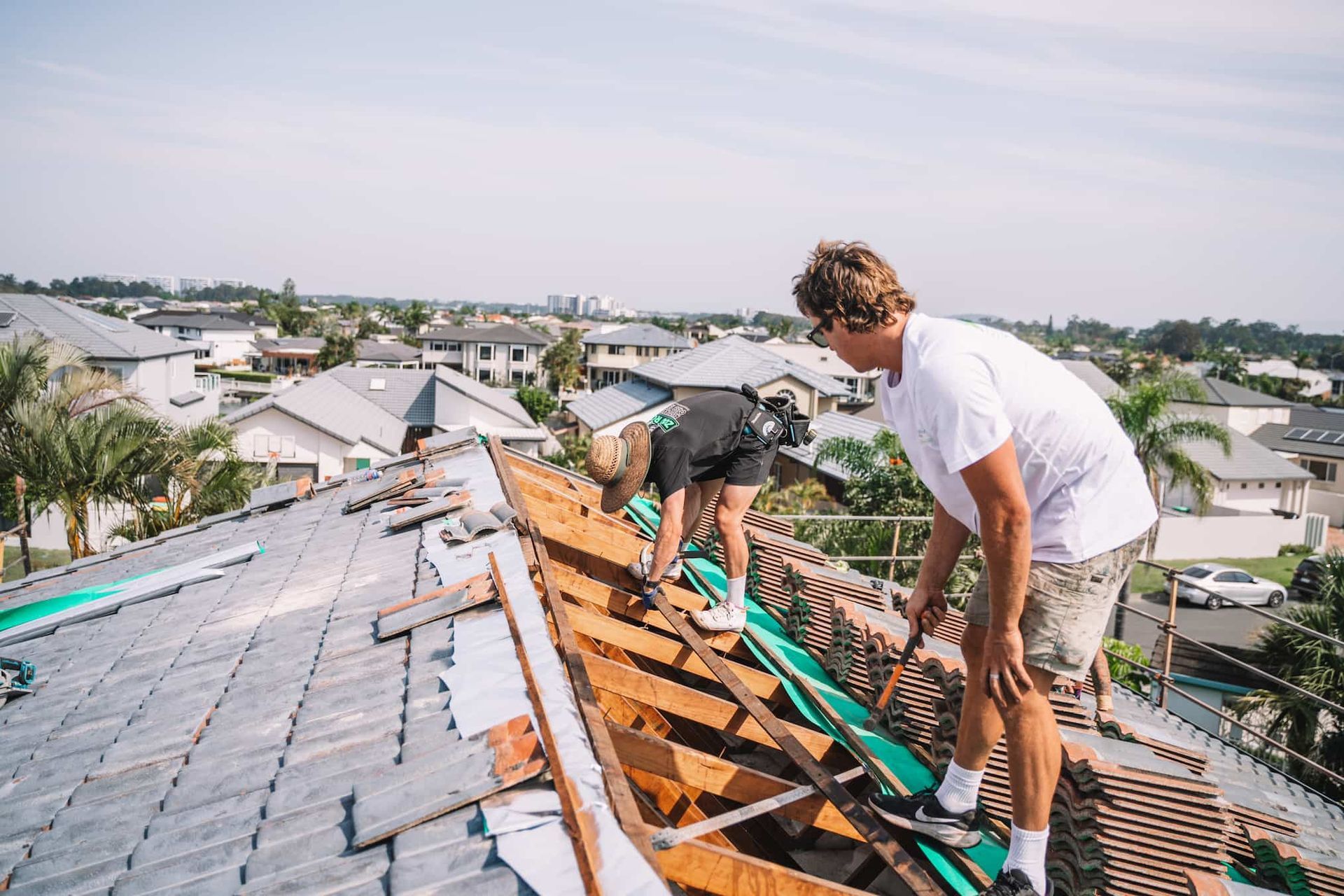Two men are working on the roof of a house.