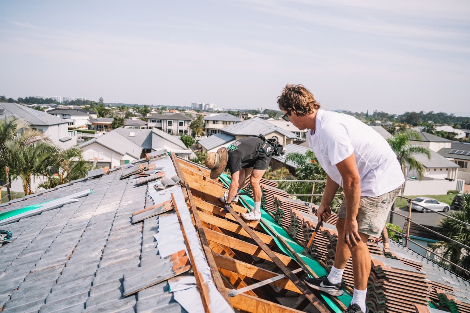 Two men are working on the roof of a house.