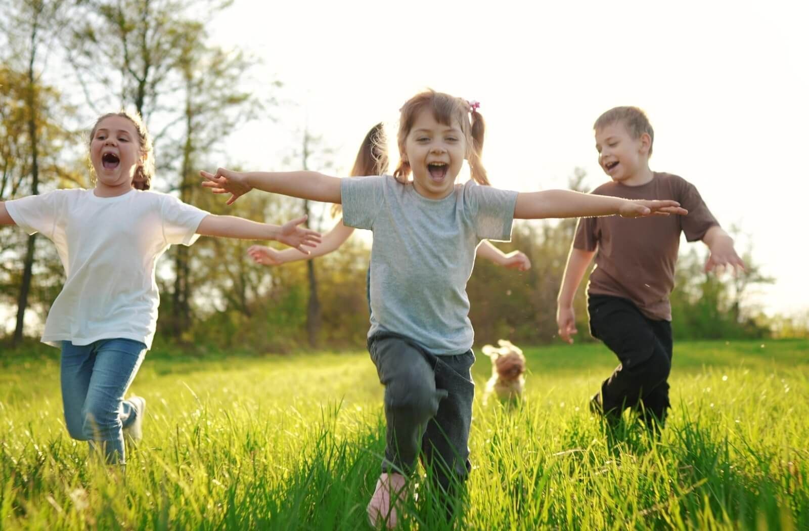 3 children running in a bright sunny field