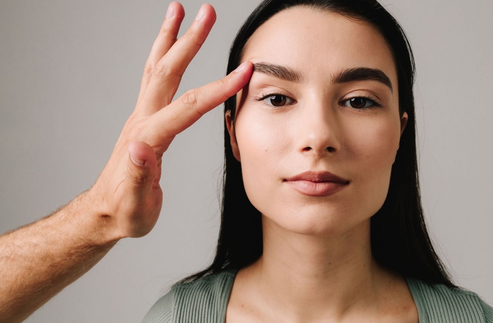 Face of a woman with a man's hand lifting the left side eye area