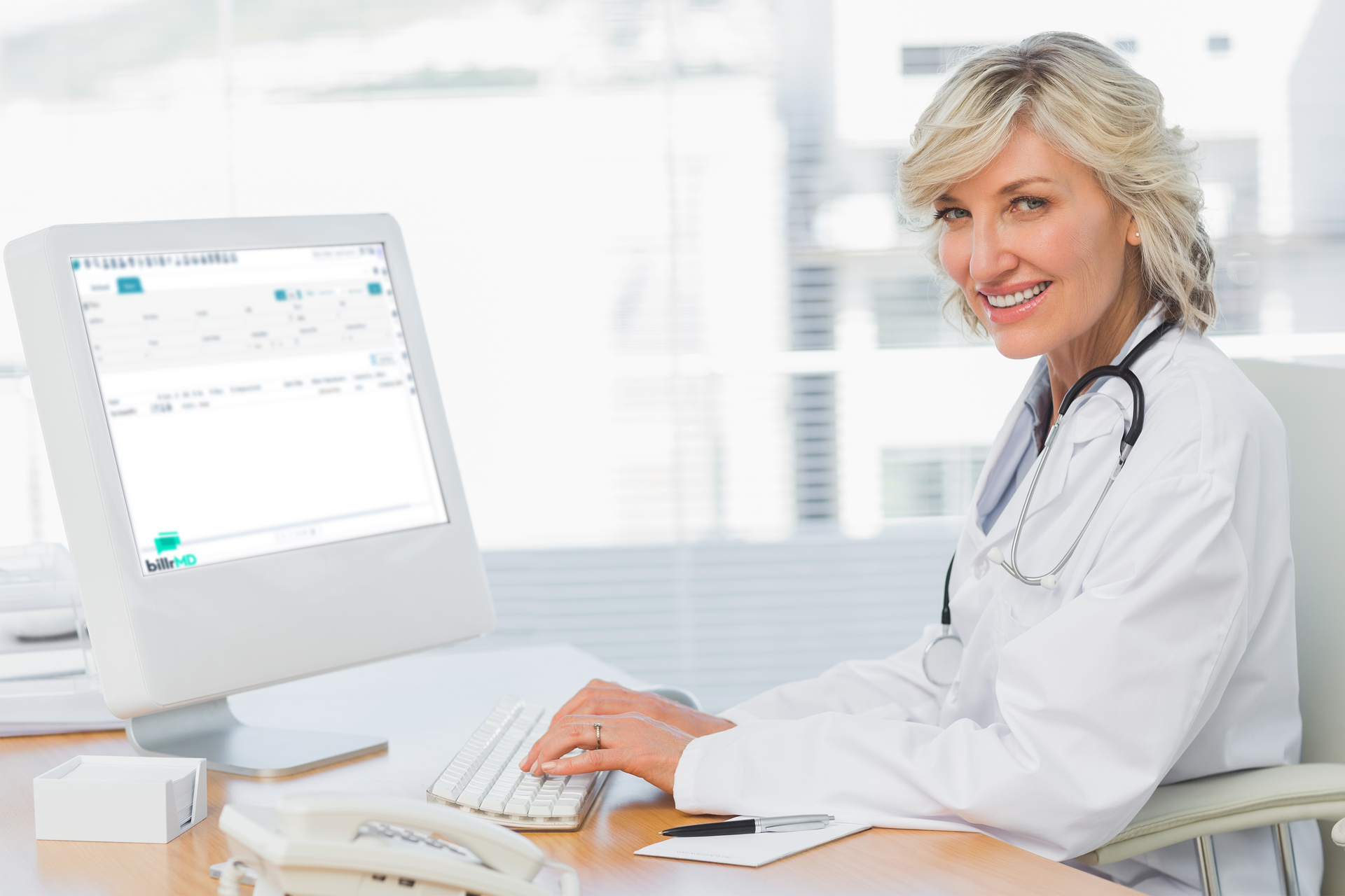 A female doctor smiling while using a medical office software on  her desktop computer.