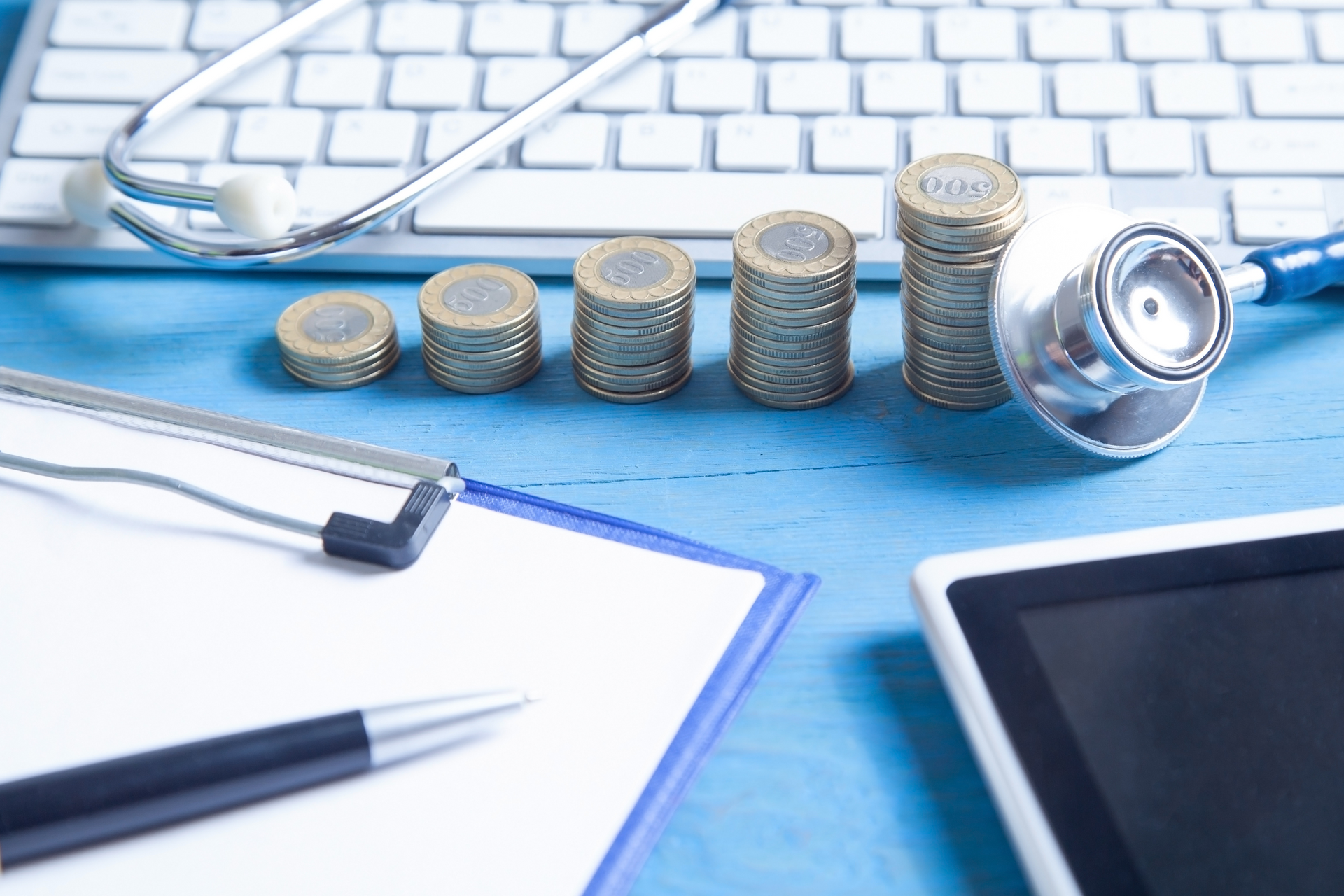 A stack of coins surrounded by medical billing and coding tools.