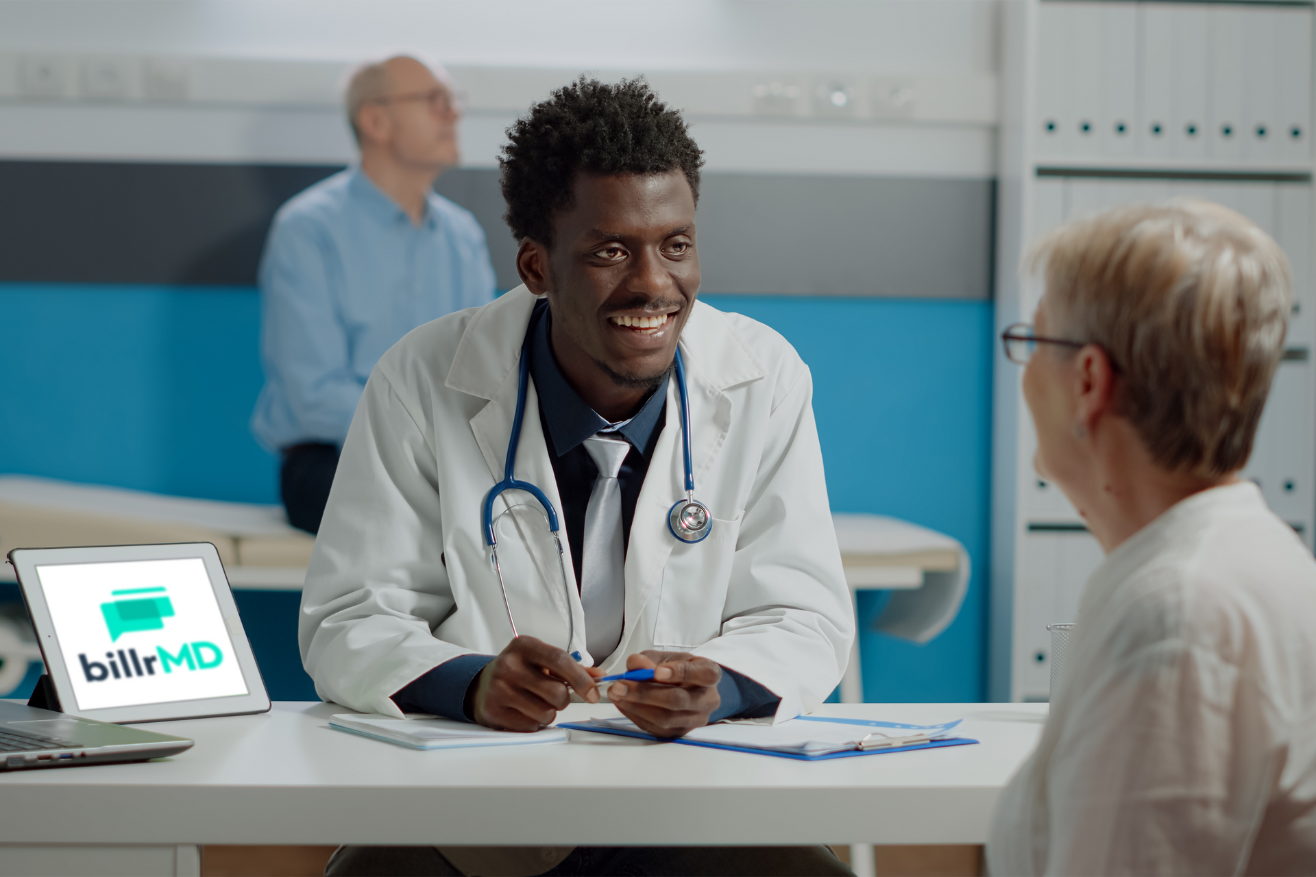 A doctor talking to a patient with a tablet on his side showing the billrMD logo on the screen.