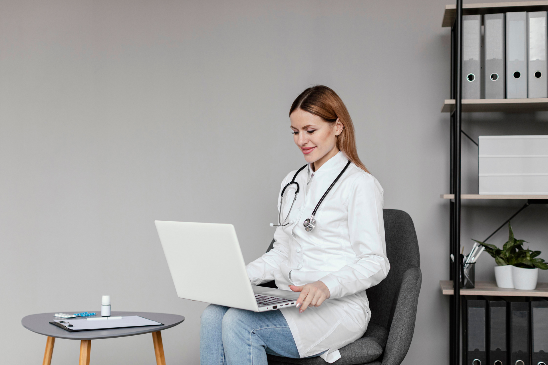 A doctor sitting on a chair with a laptop on her lap.