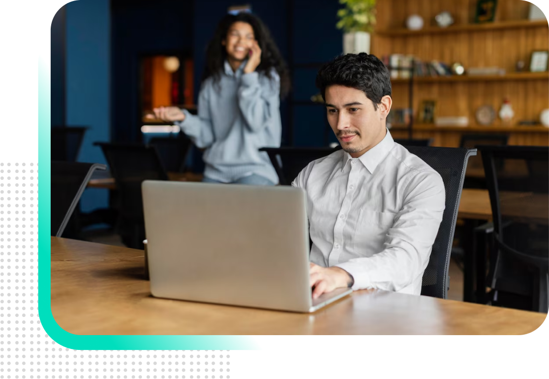 A man is sitting at a table using a laptop computer.