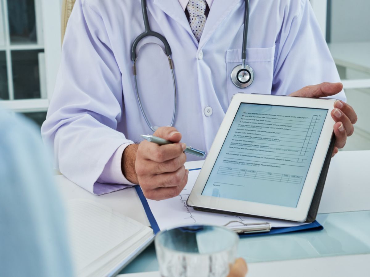 A doctor asking the patient to fill out a form in their medical practice management software