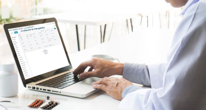 A medical biller analyzing FY 2026 ICD-10-CM updates on a dual-monitor setup using billrMD’s ICD-10-ready billing and compliance software.