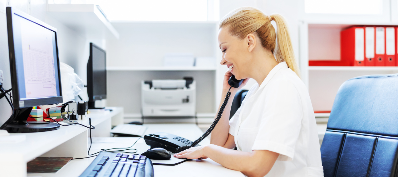 A medical administration staff smiling while on the phone.