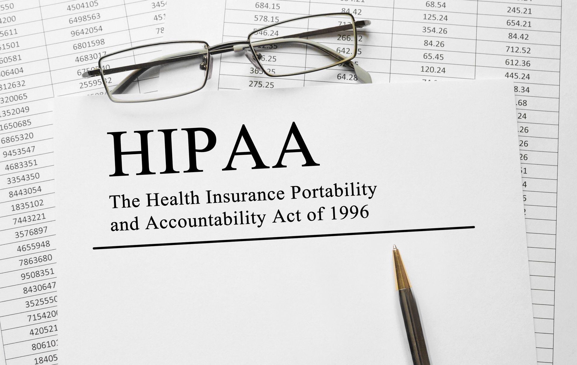 A piece of paper saying HIPAA laid on top of healthcare billing documents