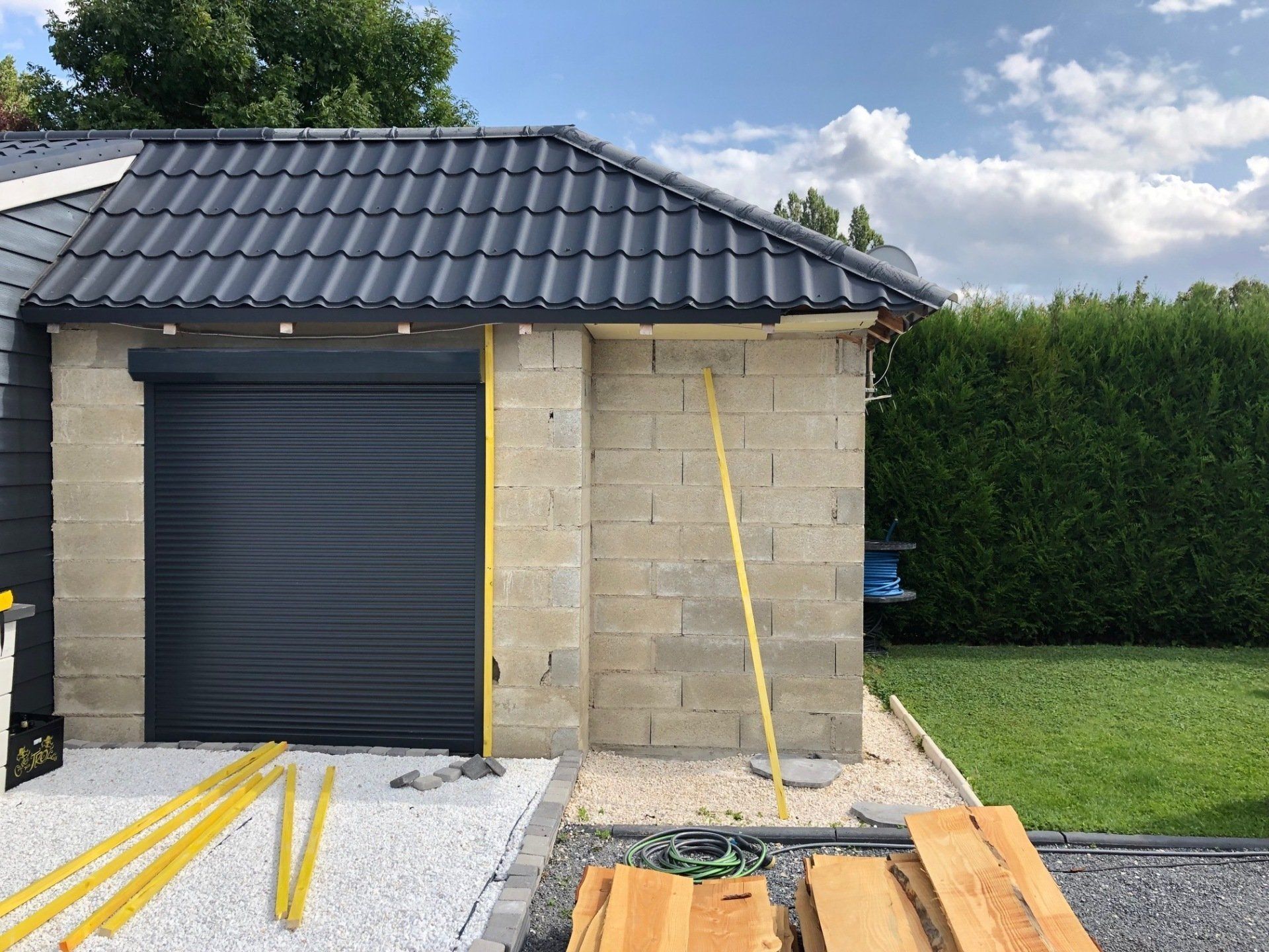 Un garage avec un toit noir est en cours de construction.