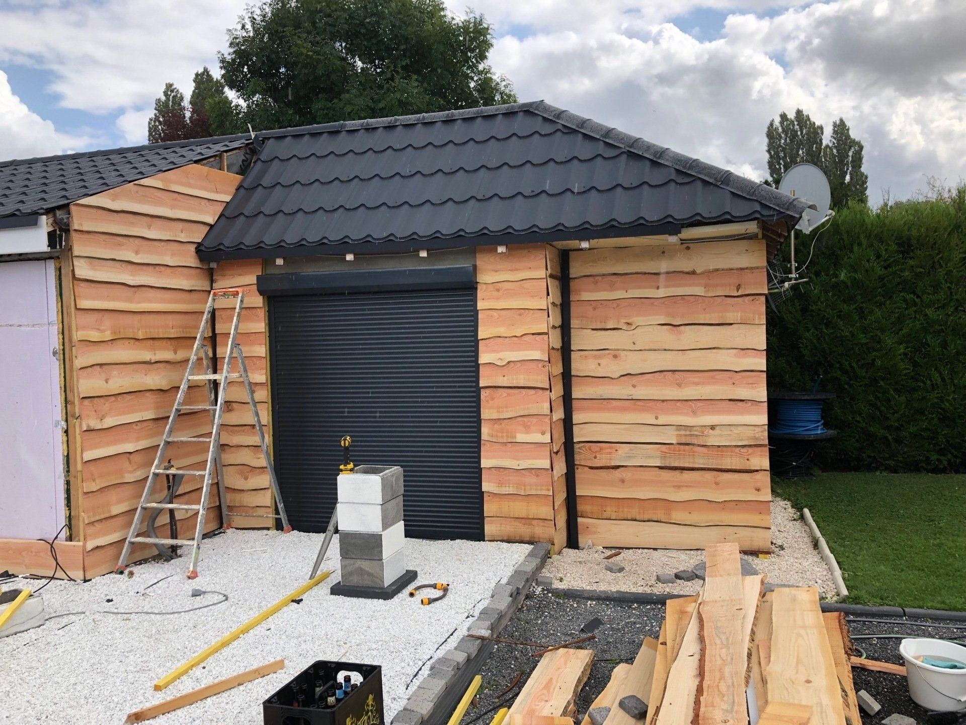 Un garage en bois avec un toit noir est en cours de construction.