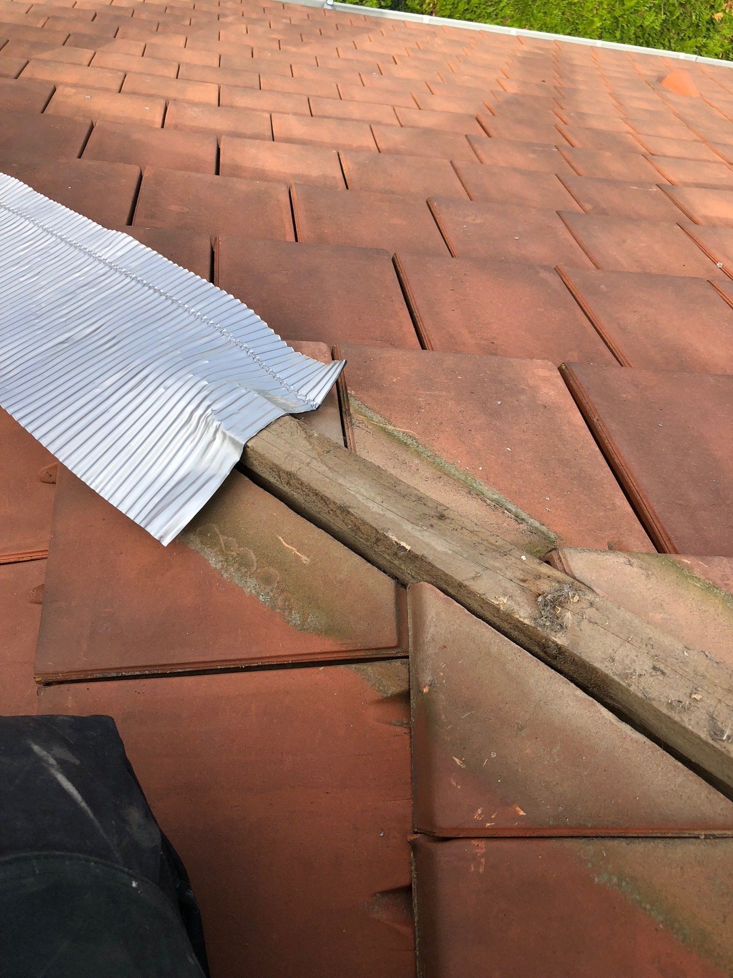 Une planche de bois est posée sur un toit en briques.