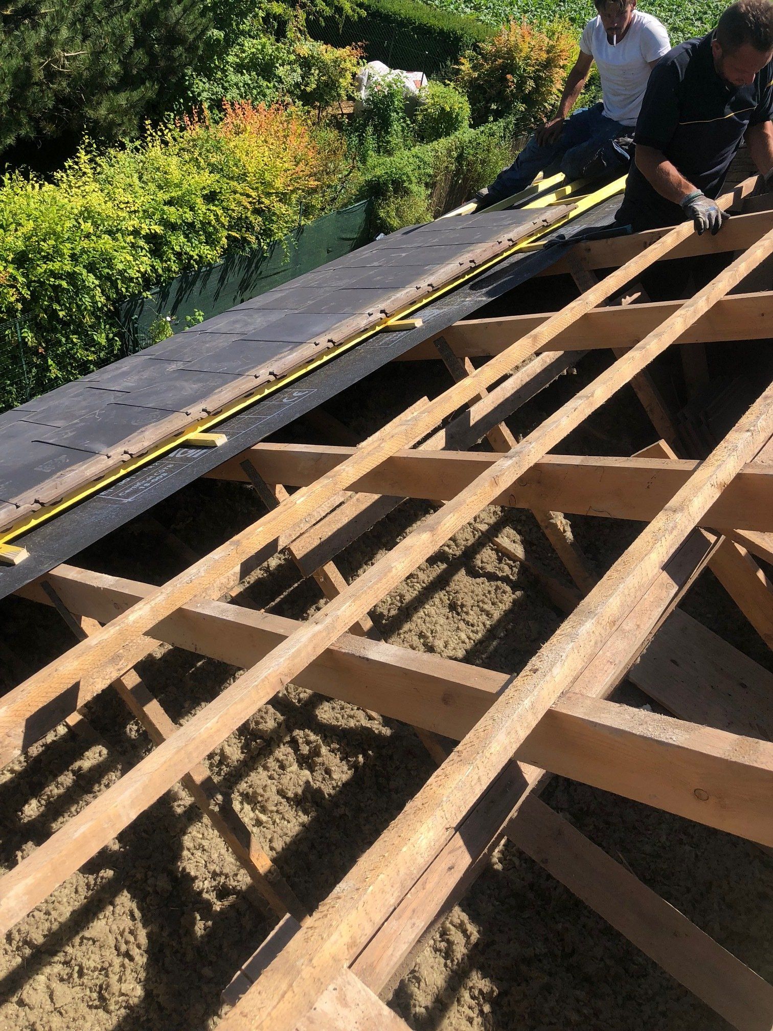 deux hommes travaillent sur un toit en bois .