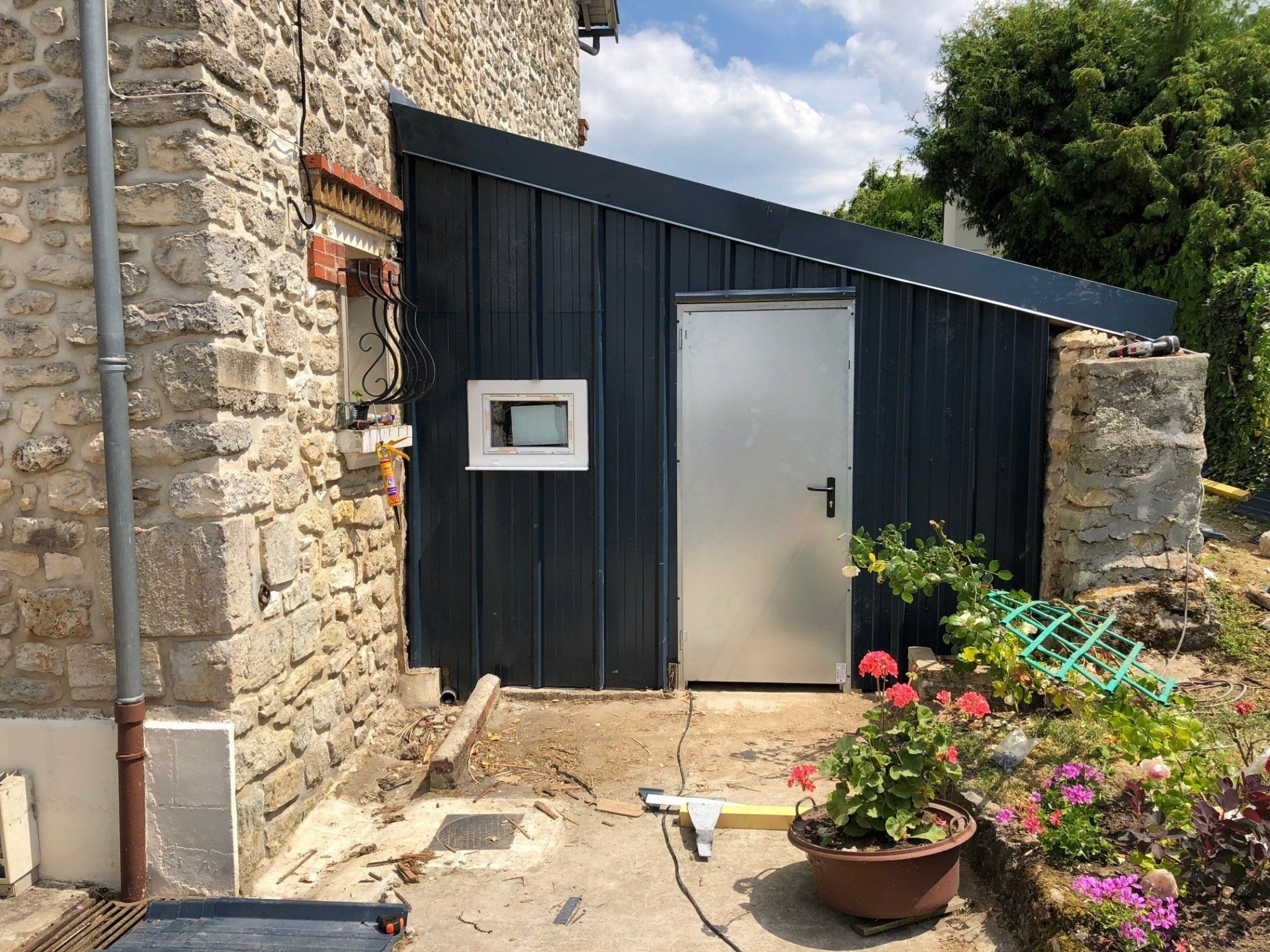 Un hangar est en cours de construction sur le côté d'un bâtiment en pierre.