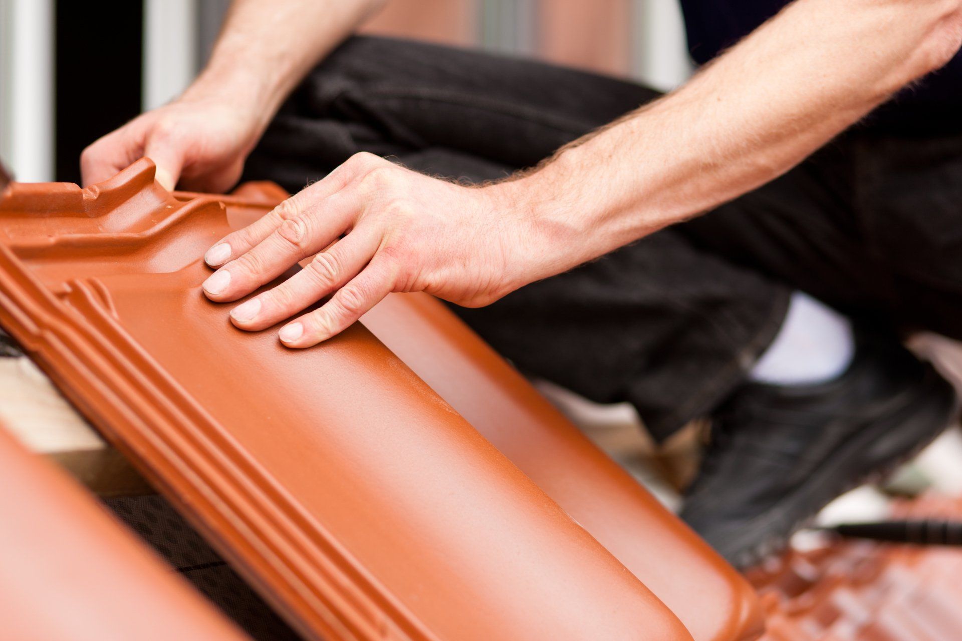 un homme est assis sur le sol tenant un tas de tuiles rouges .