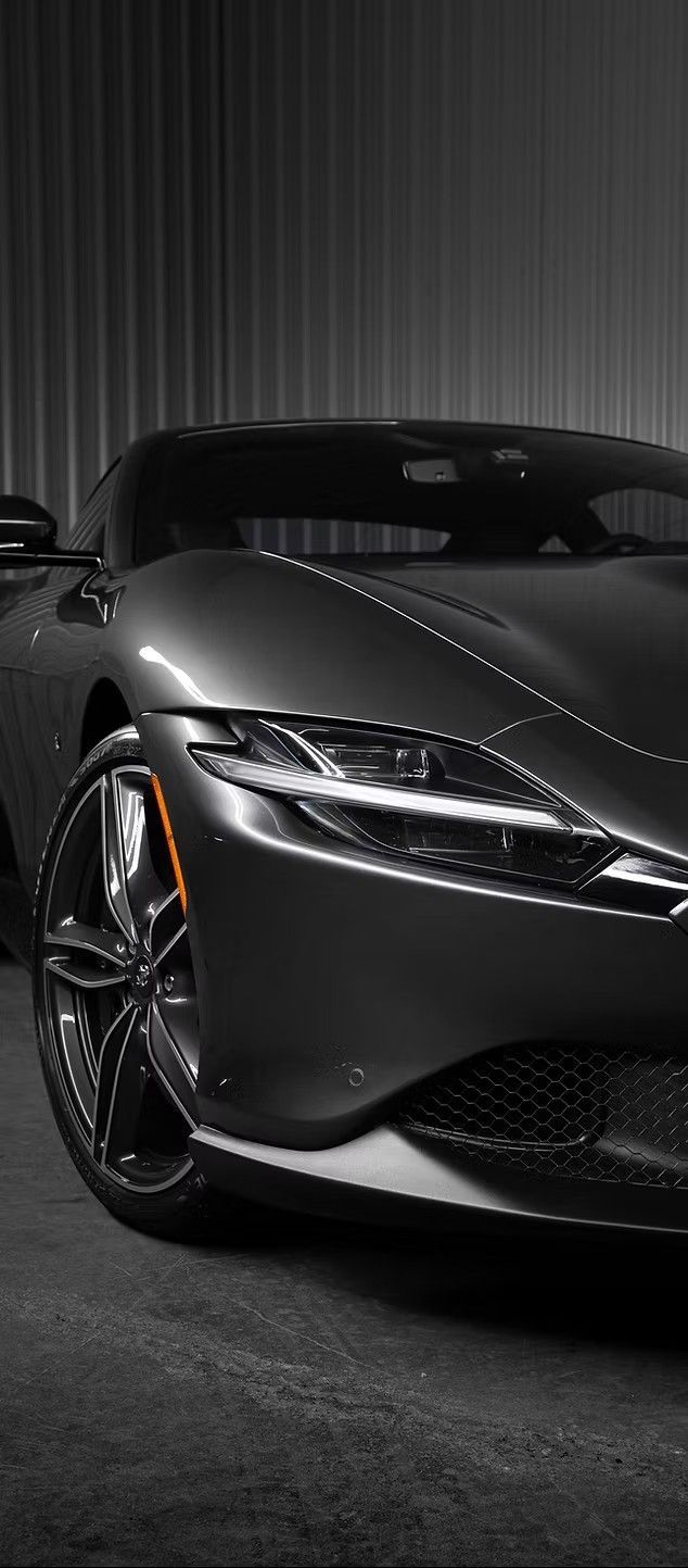 A grayscale front view of a sleek, modern sports car. The car is parked in a garage.