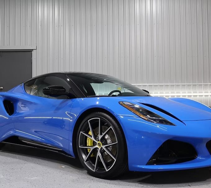 Blue Lotus Emira sports car parked indoors.