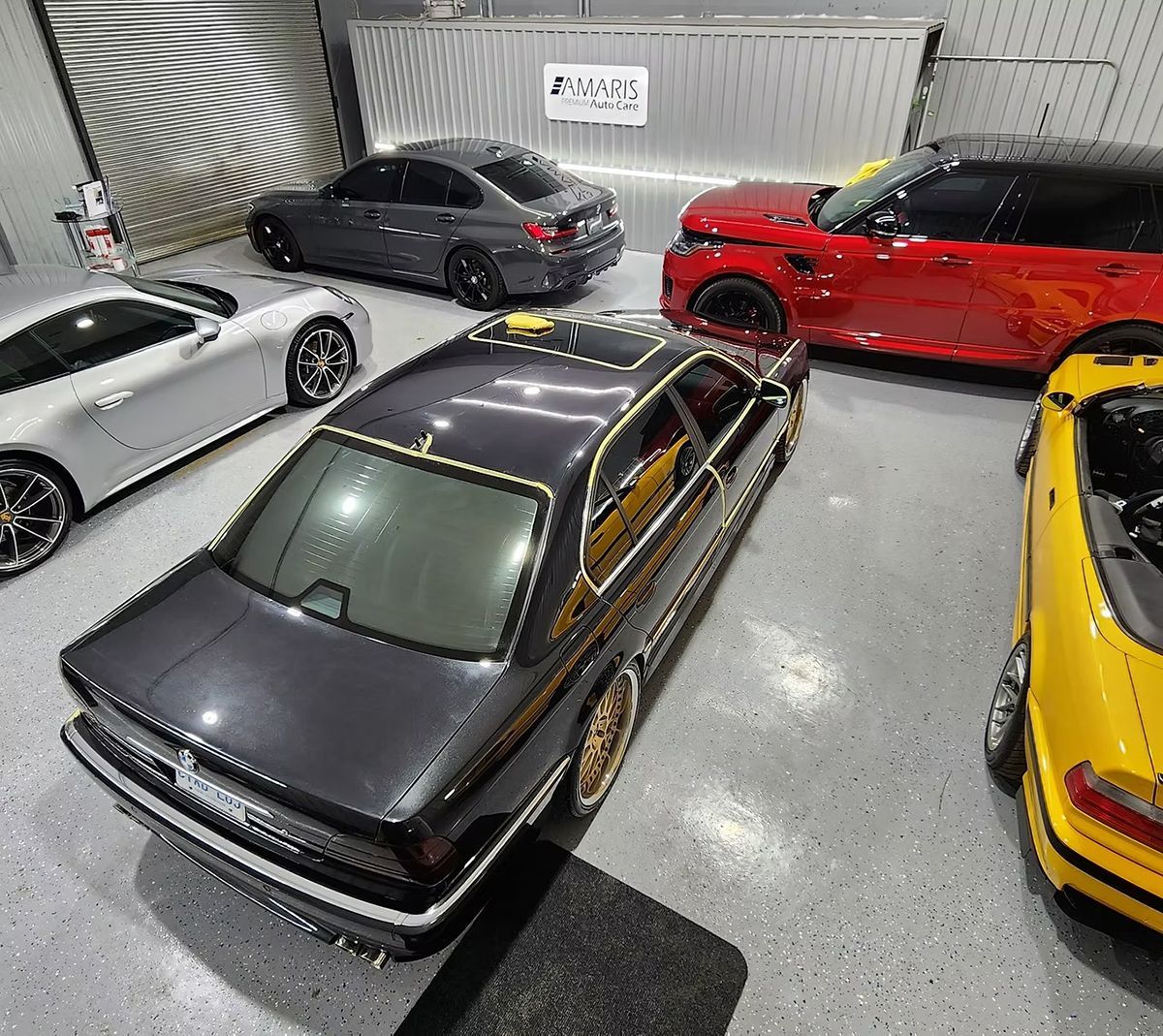 Cars parked inside a garage. Dark gray car in the center, surrounded by other vehicles in various colors.