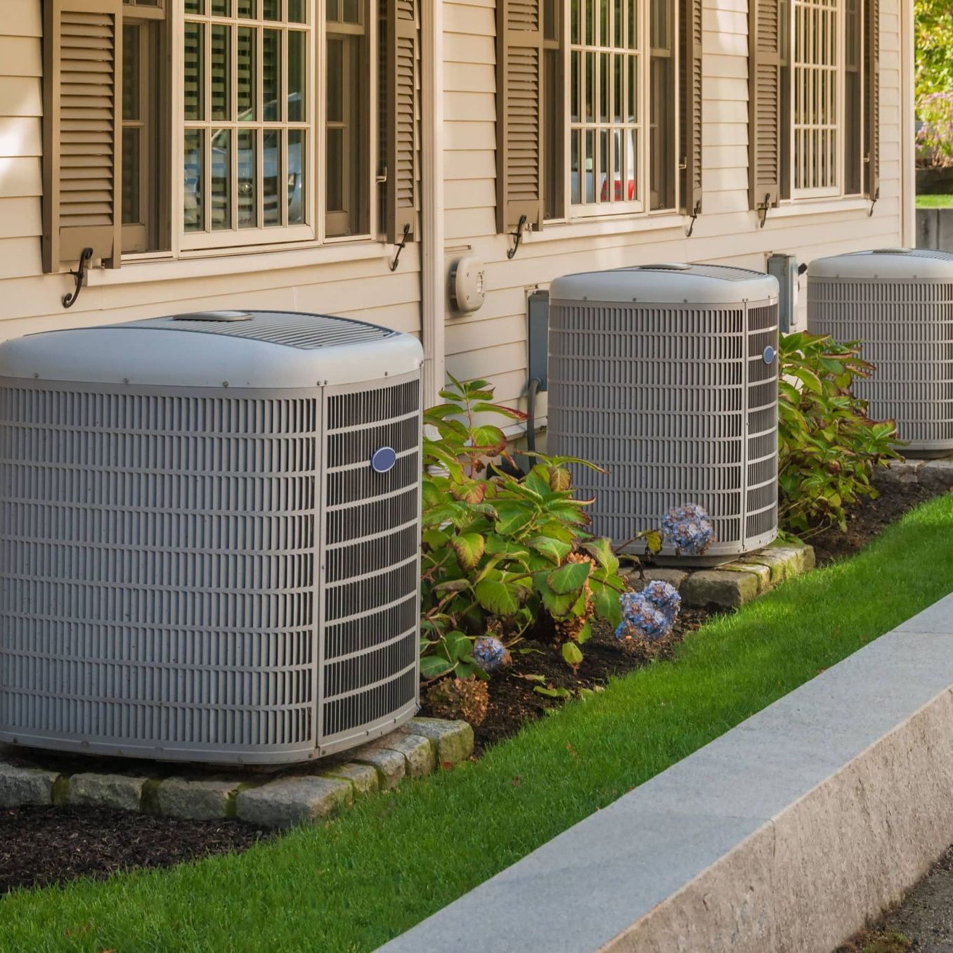 A row of air conditioners on the side of a house