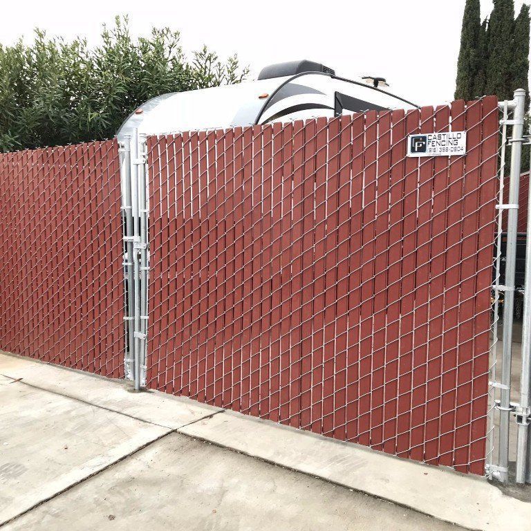 A red chain link fence with a trailer in the background.