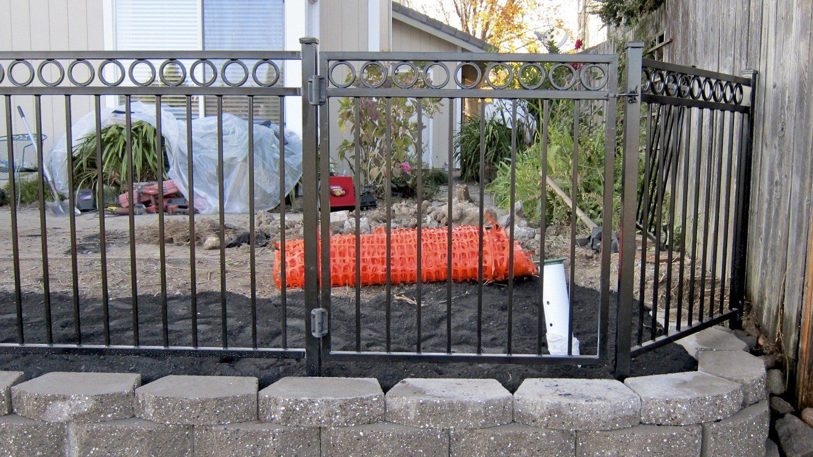 A wrought iron fence with a gate in front of a house.