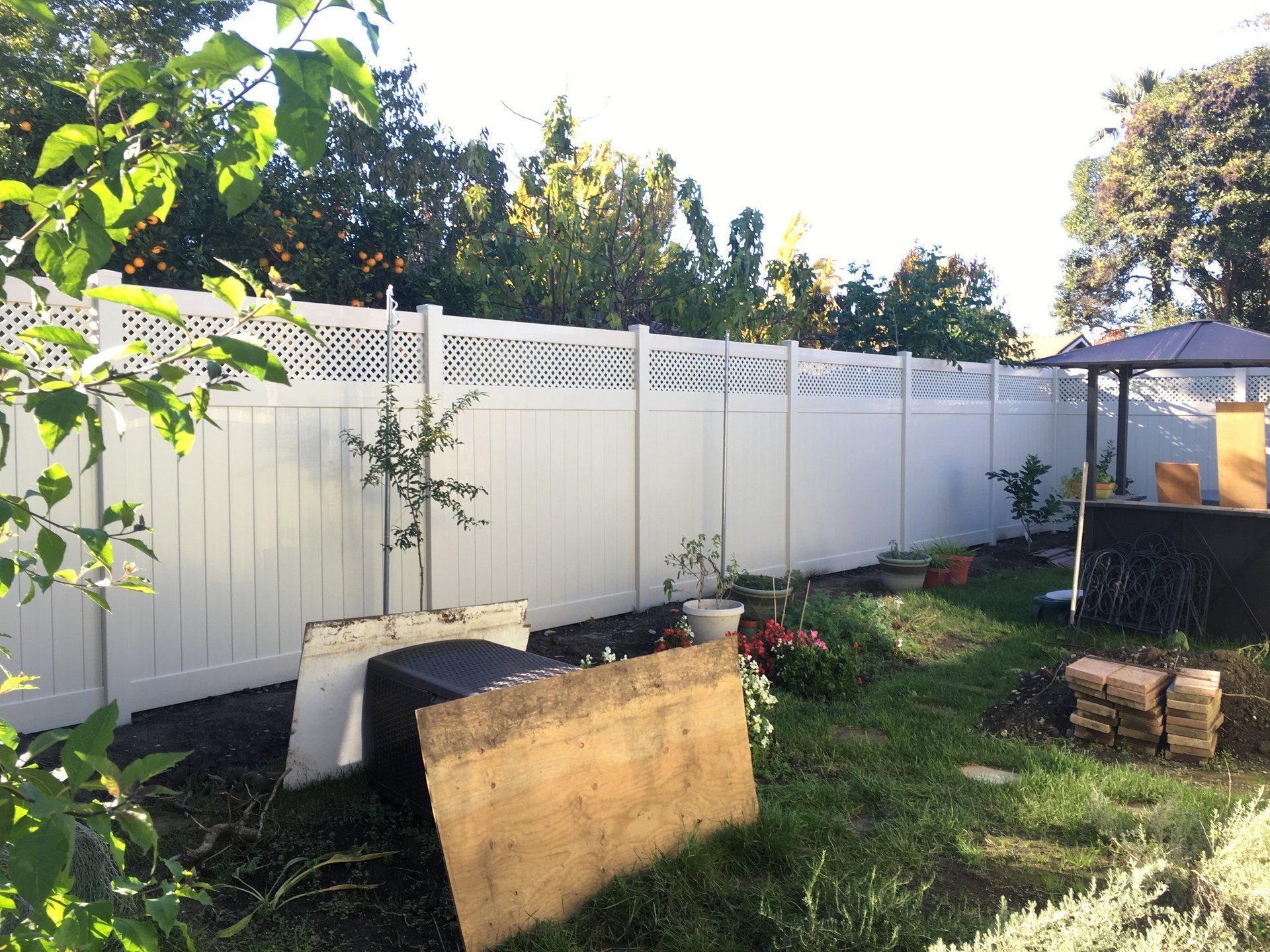 A backyard with a white fence and a gazebo