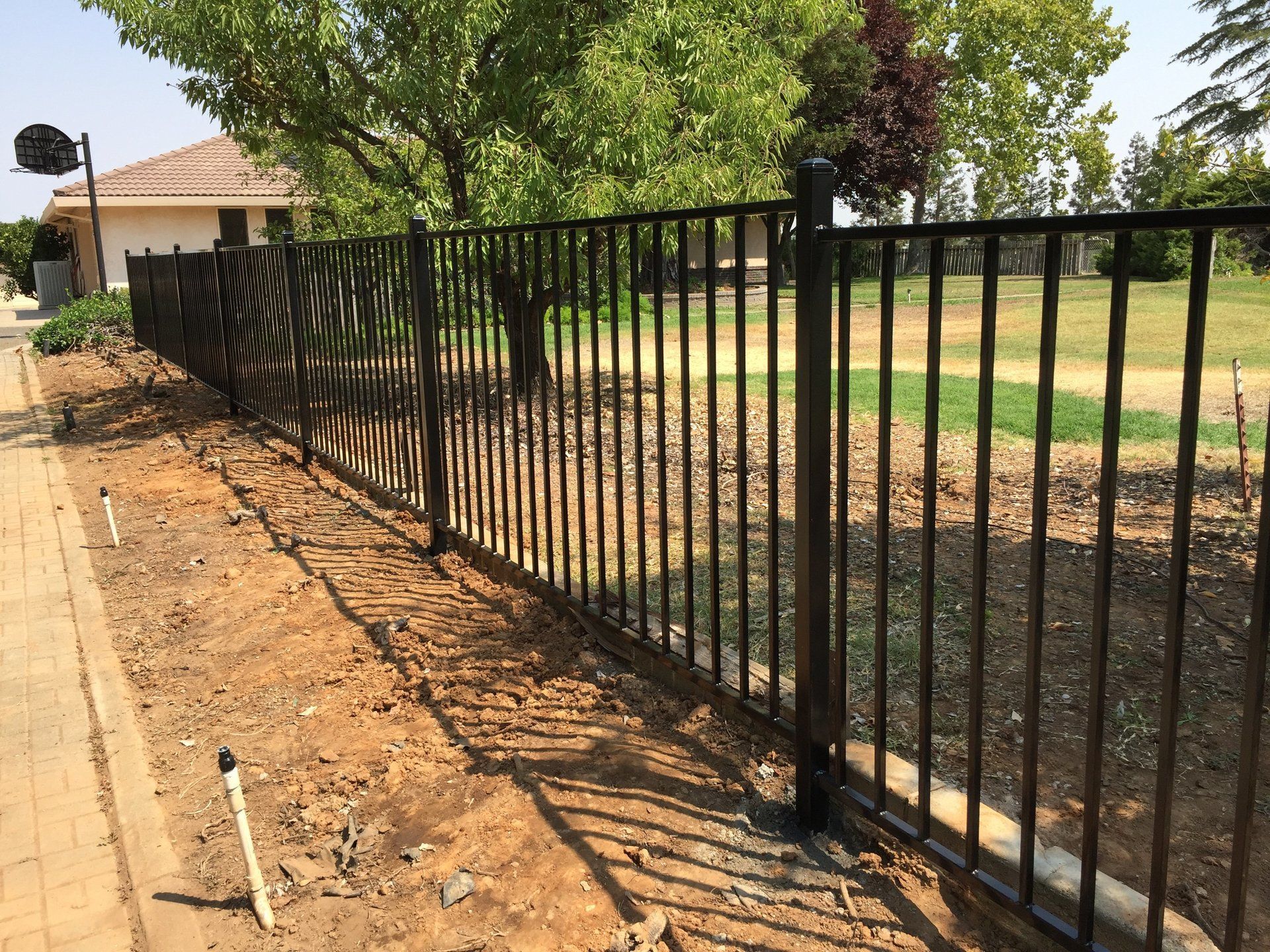 A black wrought iron fence surrounds a lush green field.