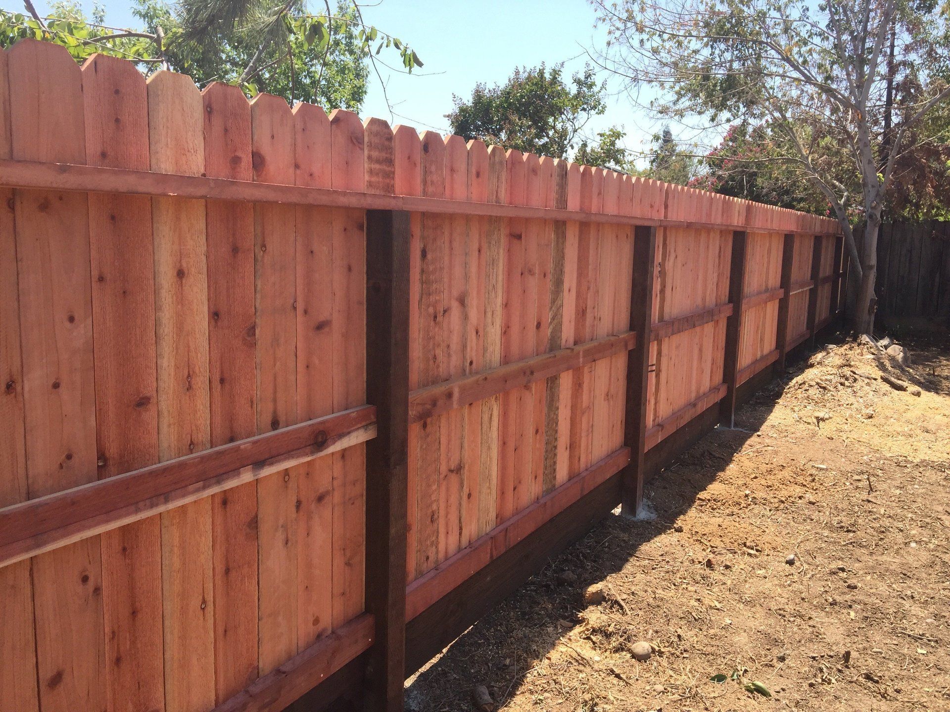 A wooden fence is sitting in the middle of a dirt field.