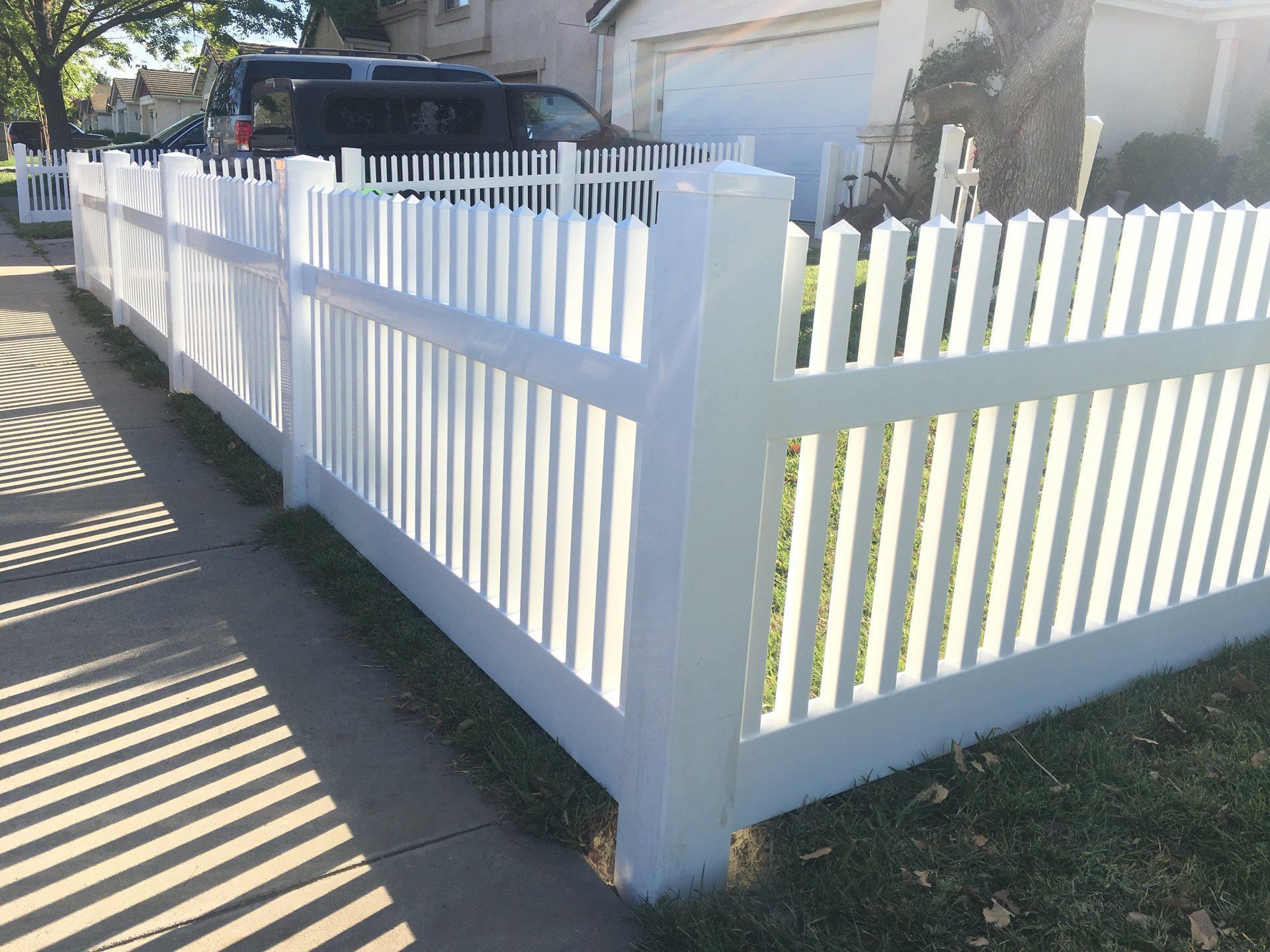 A white picket fence is in front of a house