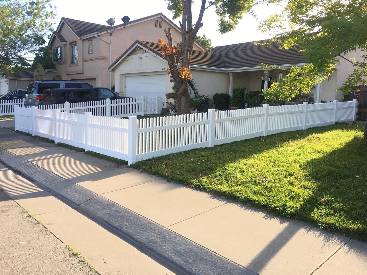 A white picket fence is in front of a house