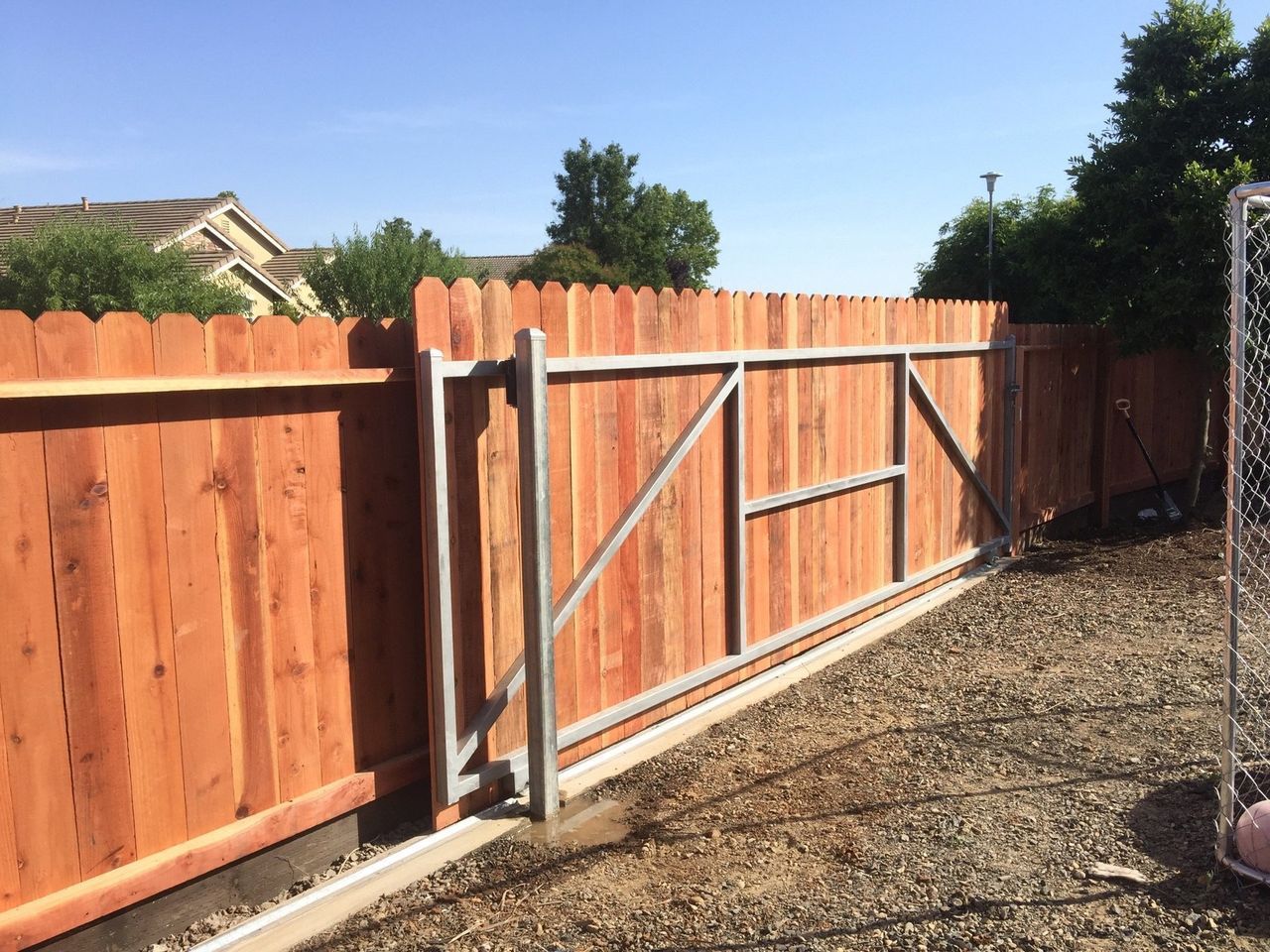 A wooden fence with a metal gate in the backyard