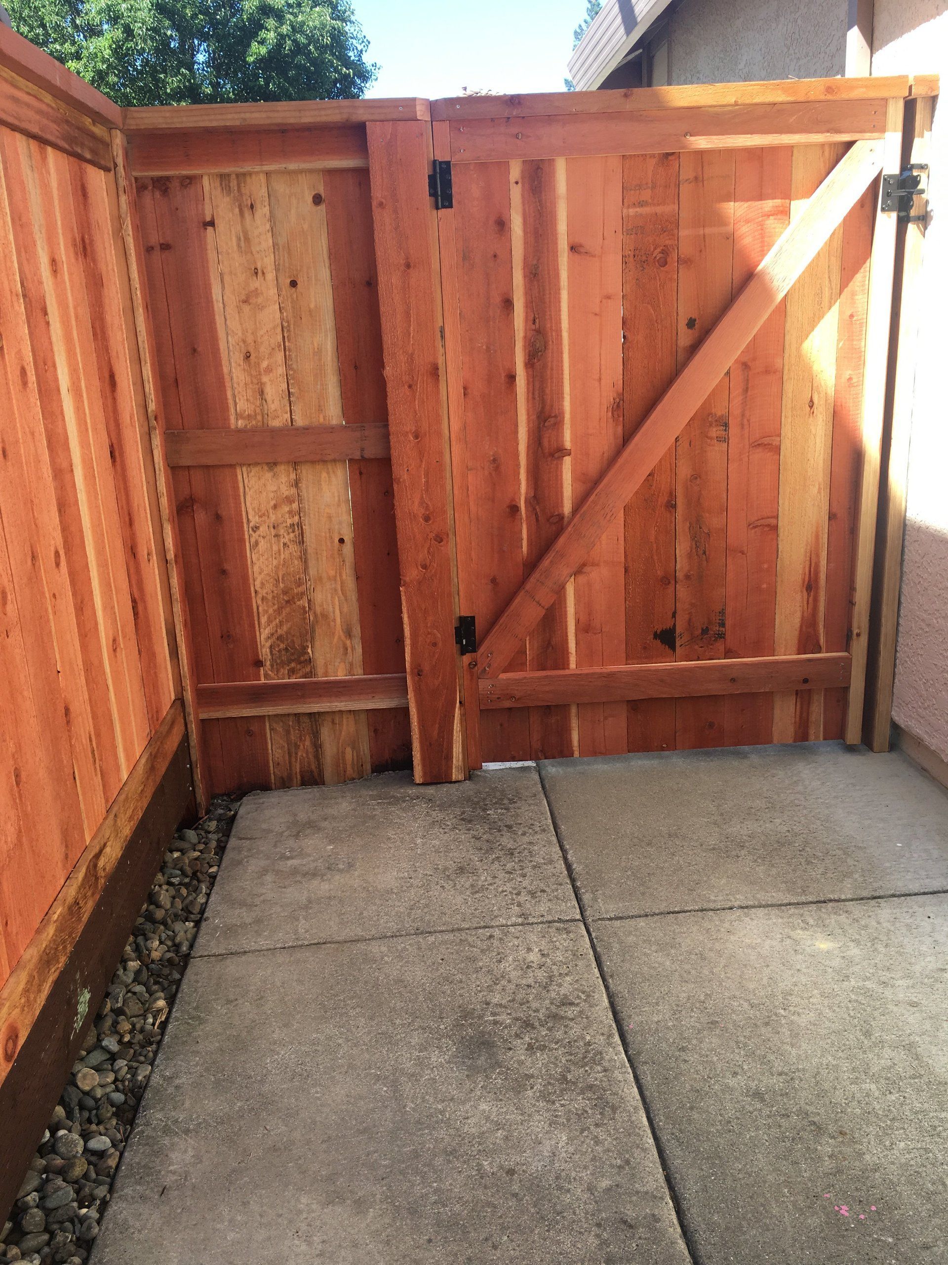 A wooden fence is sitting next to a concrete walkway.