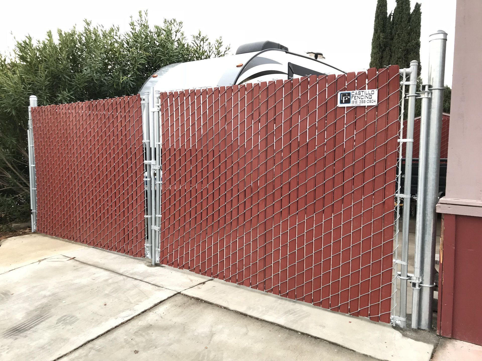 A red chain link fence with a gate in front of a building.