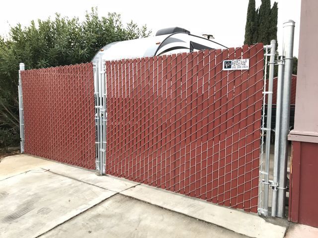 A red chain link fence is surrounding a trailer in a driveway.