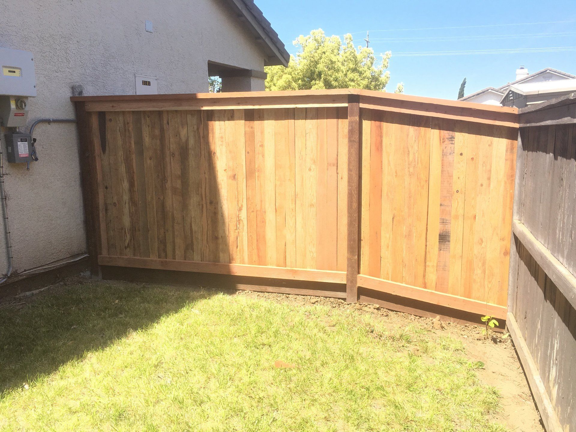 A wooden fence is in the backyard of a house.
