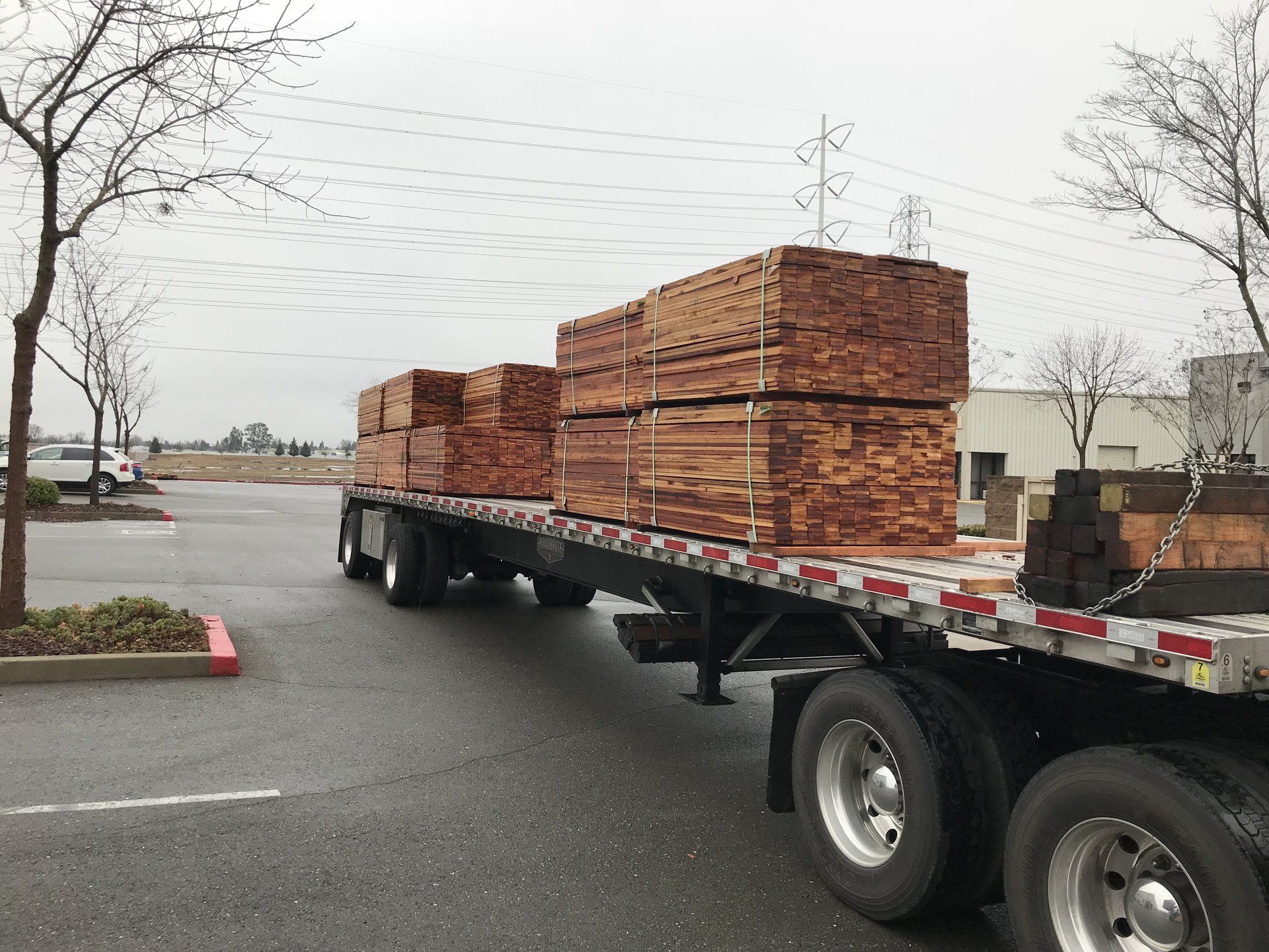 A semi truck is carrying stacks of wood on a flatbed trailer.