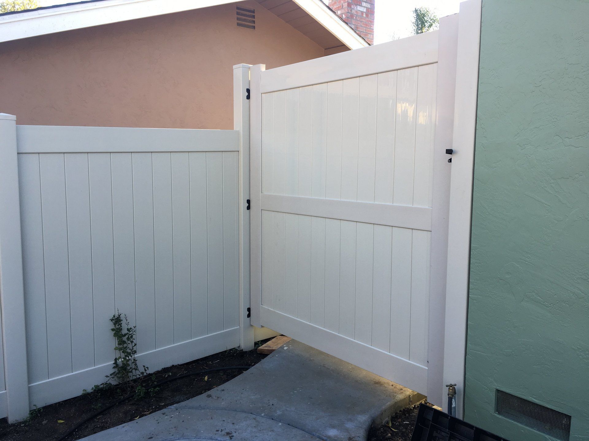 A white fence with a gate in the backyard of a house.